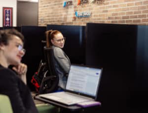 Deux clientes avec des bureaux virtuels chez 2C2B Coworking échangent dans l'aire ouverte. 